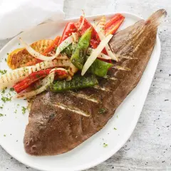 Sole grillé, garni de poivrons et d'oignons grillés, saupoudré de persil frais. Un plat savoureux et coloré.