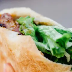 Kebab w bułce z mięsem i świeżą sałatą.