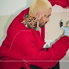 Quebonafide w czerwonym swetrze steruje marionetką, jakby tworzył swoje utwory.