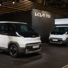 Dwa białe samochody Kia PV5 na wystawie. Jeden to podwozie, drugi to wersja z zabudową.