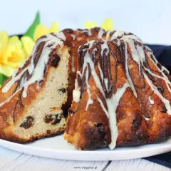 Pyszna babka drożdżowa Ani gotuje, udekorowana lukrem i czekoladą, z rodzynkami w środku.