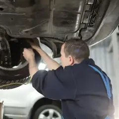 Mechanik wymienia płyn hamulcowy w samochodzie podniesionym na podnośniku.
