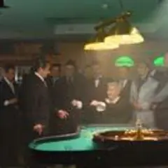 Wielki Szu obsada w kasynie, przy stole do ruletki. Mężczyźni w garniturach obserwują grę.