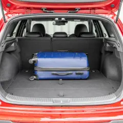 Otwarty bagażnik czerwonego Hyundai i30 kombi z niebieską walizką. Sprawdź pojemność bagażnika na podróż!