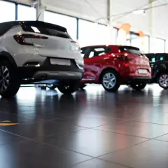 Tre auto, bianca, rossa e nera, in un concessionario. La valutazione autoscout è facilitata dalla vista posteriore dei veicoli.