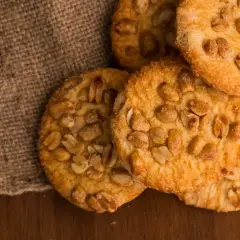 Knusprige erdnuss schoko cookies, verlockend auf Jute und Holz arrangiert.