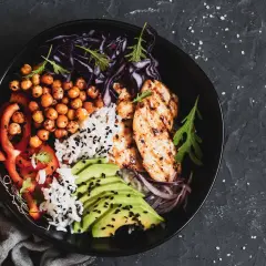 Un bol savoureux avec poulet grillé, riz, pois chiches, avocat et légumes. Parfait pour l'alimentation musculation.