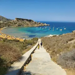 Malta, kwiecień: słoneczna pogoda zachęca do spaceru schodami w dół do zatoki z turkusową wodą i łodziami.