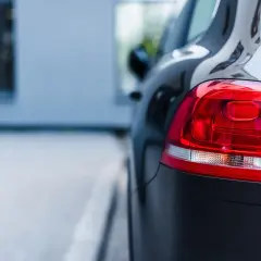 Ciemny samochód, gotowy na uber paczkę. Błyszczący lakier i czerwone światła z tyłu.