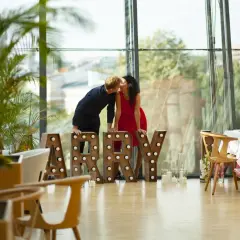 Para zapatrzona w siebie przy literach "MARRY" w nowoczesnym wnętrzu z widokiem na miasto. Idealne miejsce na zaręczyny Polska.