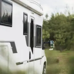 Biały kamper w drodze do Bieszczad, wśród zielonych lasów.