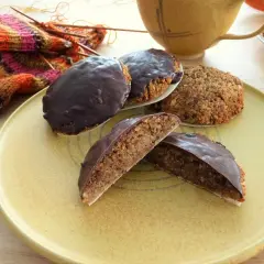 Schokoladen-Lebkuchen, ein köstliches Lebkuchen Rezept ohne Mehl, liegen auf einem Teller neben Strickzeug und einer Tasse.