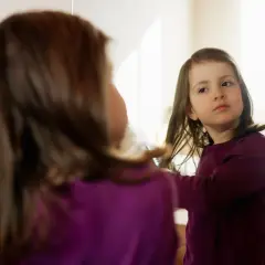 Dziewczynka czesze włosy przed lustrem, budując poczucie własnej wartości i samoocenę.