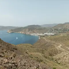 Vista panorámica de la costa de Almería, con el mar azul, un pueblo blanco y el paisaje árido del cerro negro.