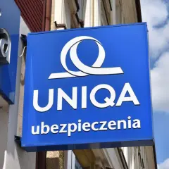 Niebieski szyld z logo i napisem "UNIQA ubezpieczenia". Firma UNIQA oferuje ubezpieczenia.