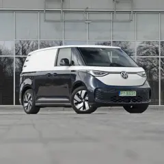 Dwukolorowy Volkswagen ID. Buzz 7 osobowy, zaparkowany przed nowoczesnym budynkiem z lustrzanymi oknami.