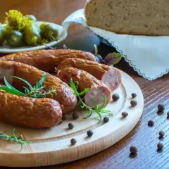 Smaczna kiełbasa na desce z rozmarynem i pieprzem. Zastanawiasz się, ile metrów jelit na 10 kg kiełbasy?