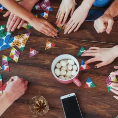 Hände legen bunte Spielsteine auf den Tisch. Ein gemütlicher Abend mit Zeit mit den liebsten Brettspiele.