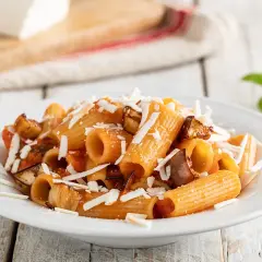 Piatto di pasta alla norma ricetta originale con melanzane fritte, pomodoro e ricotta salata grattugiata.