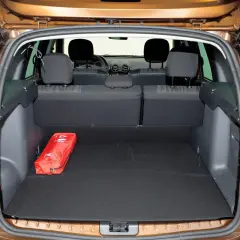 Otwarty bagażnik Dacia Duster, pokazujący jego pojemność. Czerwona apteczka leży na czarnym dywaniku.