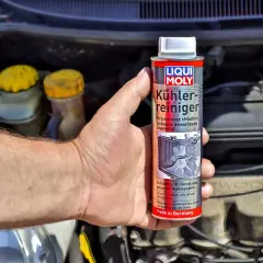 Ręka trzyma puszkę preparatu Liqui Moly do czyszczenia chłodnic. To klucz do tego, jak odkamienić chłodnicę.