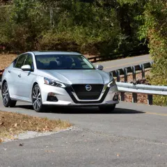 Srebrny Nissan Altima na krętej drodze, gotowy do przeniesienia własności samochodu.