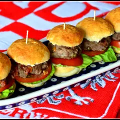 Pięć apetycznych mini burgery na zimno, ułożonych na talerzu, z pomidorami, sałatą i mięsem. Idealne na letnie przyjęcie.