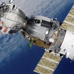 Sojuz MS-03, jeden z wielu satelitów krążących wokół Ziemi, na tle błękitnego nieba i chmur.