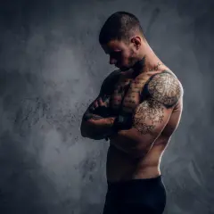 Mężczyzna z licznymi tatuażami na ciele, które tworzą jego drugą skórę po tatuazu.