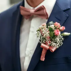 Elegancka muszka do granatowego garnituru, ozdobiona bukiecikiem różowych różyczek i gipsówki.