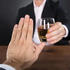 Mężczyzna odrzuca kieliszek alkoholu, zastanawiając się, jaki alkohol ma najmniej kalorii.