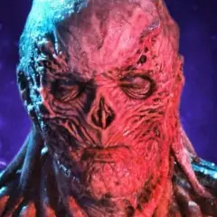 Le visage déformé et rougeaud de Vecna, le monstre de Stranger Things, se détache sur un fond violet.