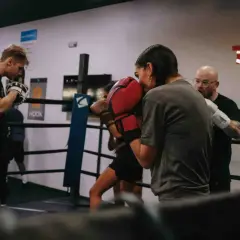 Intense soviet boxing training session in a ring. A coach observes as two boxers spar, their gloves a blur of motion.