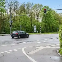 Ein dunkler Golf fährt über eine nasse Straße, die Ampel zeigt rot. Hoffentlich hat er nicht bei rot geblitzt.