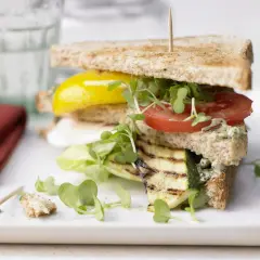 Ein saftiges, vegetarisches Sandwich mit gegrilltem Zucchini, Tomate, gelber Paprika und frischen Sprossen auf Vollkorntoast.