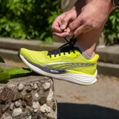Dłoń wiąże sznurówki jaskrawożółtego buta Puma Deviate Nitro 3, gotowego na bieg.