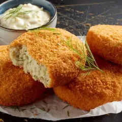 Crujientes croquetas de merluza doradas, una partida revela su interior tierno. Servidas con una cremosa salsa y eneldo fresco.