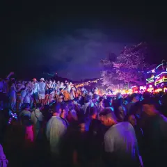 Stor folkmassa festar under neonljus på Koh Phangan, Thailand.