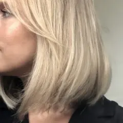 En kvinna med blont hår i en lobklippning, med en naturlig sminkning som framhäver hennes ansiktsdrag. Perfekt för smink tips.