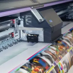 Drukarka wielkoformatowa tworzy obraz z pastelowymi barwami. Widać głowicę drukującą i rolkę z wydrukiem.