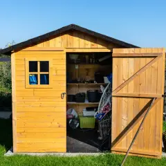 Drewniany domek narzędziowy z otwartymi drzwiami, pełen narzędzi i akcesoriów ogrodowych. Idealne miejsce, co pod domek narzedziowy, na przechowywanie wszystkiego, co potrzebne w ogrodzie.