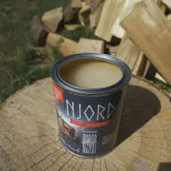 Otwarta puszka gruntu odcinającego NJORD na pniu drewna, w tle stos drewna opałowego.