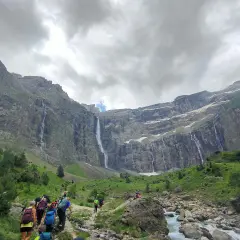 Senderos de Gavarnie: excursionistas caminan hacia impresionantes cascadas en un valle montañoso.
