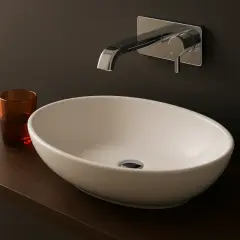 Elegancka, mała umywalka nablatowa 25 cm w nowoczesnej łazience. Obok szklanka z wodą.