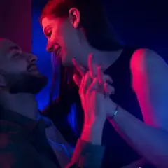 Para zbliża się do siebie w blasku neonów. Ich dłonie splatają się, tworząc intymną chwilę, która sugeruje seks bez penetracji.