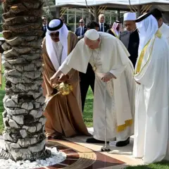 Papież Franciszek i przywódca Zjednoczonych Emiratów Arabskich wspólnie podlewają drzewo. W tle widać ludzi w tradycyjnych strojach, jakby na spotkaniu z muezinem.