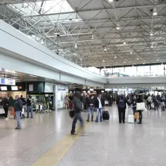 Tłoczny terminal lotniska Rome Ciampino, ludzie z bagażami czekają w kolejce do odprawy.