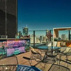 Elegancki ether rooftop bar z widokiem na miasto. Kolorowy bar, stoliki i wygodne fotele zapraszają do relaksu.