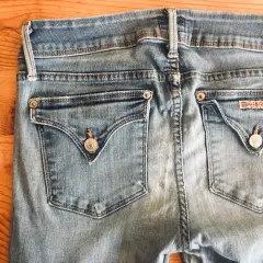 A spool of grey thread sits beside the back pockets of light blue jeans, ready for invisible mending.