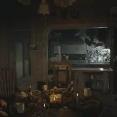 Mroczna jadalnia z obficie zastawionym stołem i śpiącym mężczyzną. W tle kuchnia, jak z poradnika Resident Evil 7.